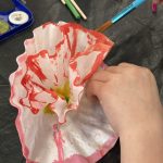 Child painting a coffee filter flower